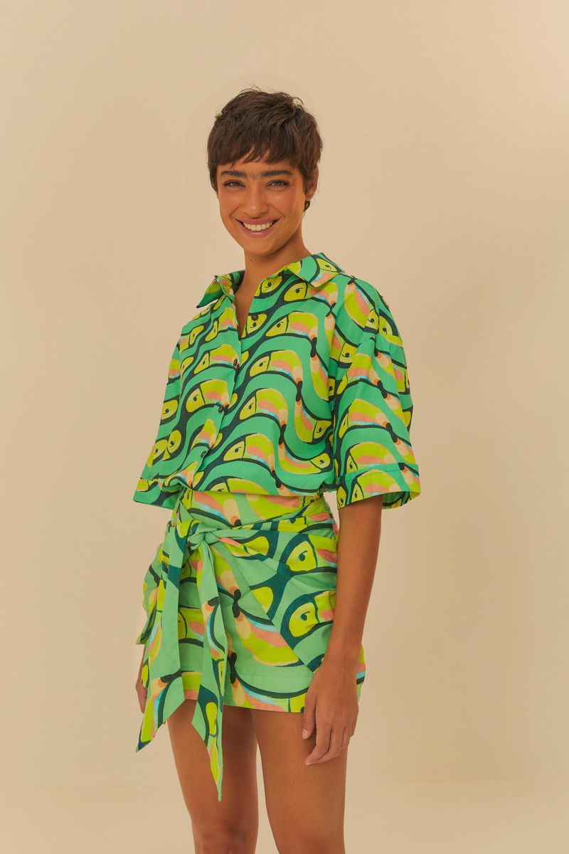Modelo usando pantalón estampado con diseño tropical y camisa combinada, vista frontal.