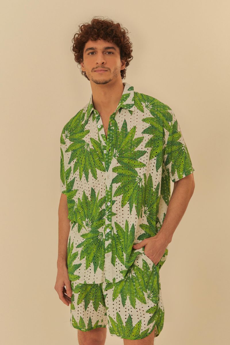 Modelo vistiendo camisa y pantalón corto estampado con diseño botánico de hojas verdes sobre fondo blanco.
