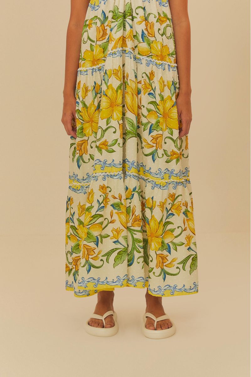 Vestido largo estampado con flores amarillas y detalles azules, combinado con sandalias estampadas.