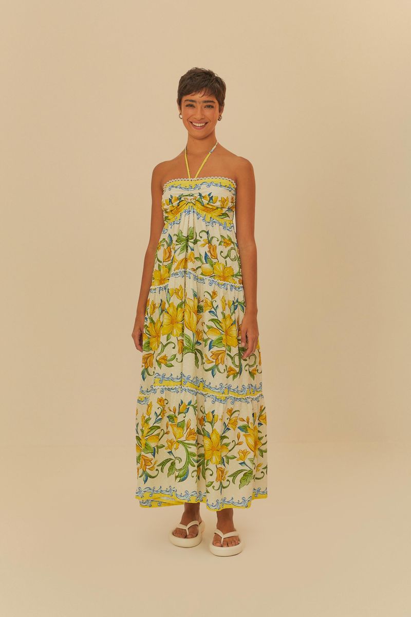 Vista trasera del vestido largo estampado con flores amarillas y detalles azules, combinado con sandalias.