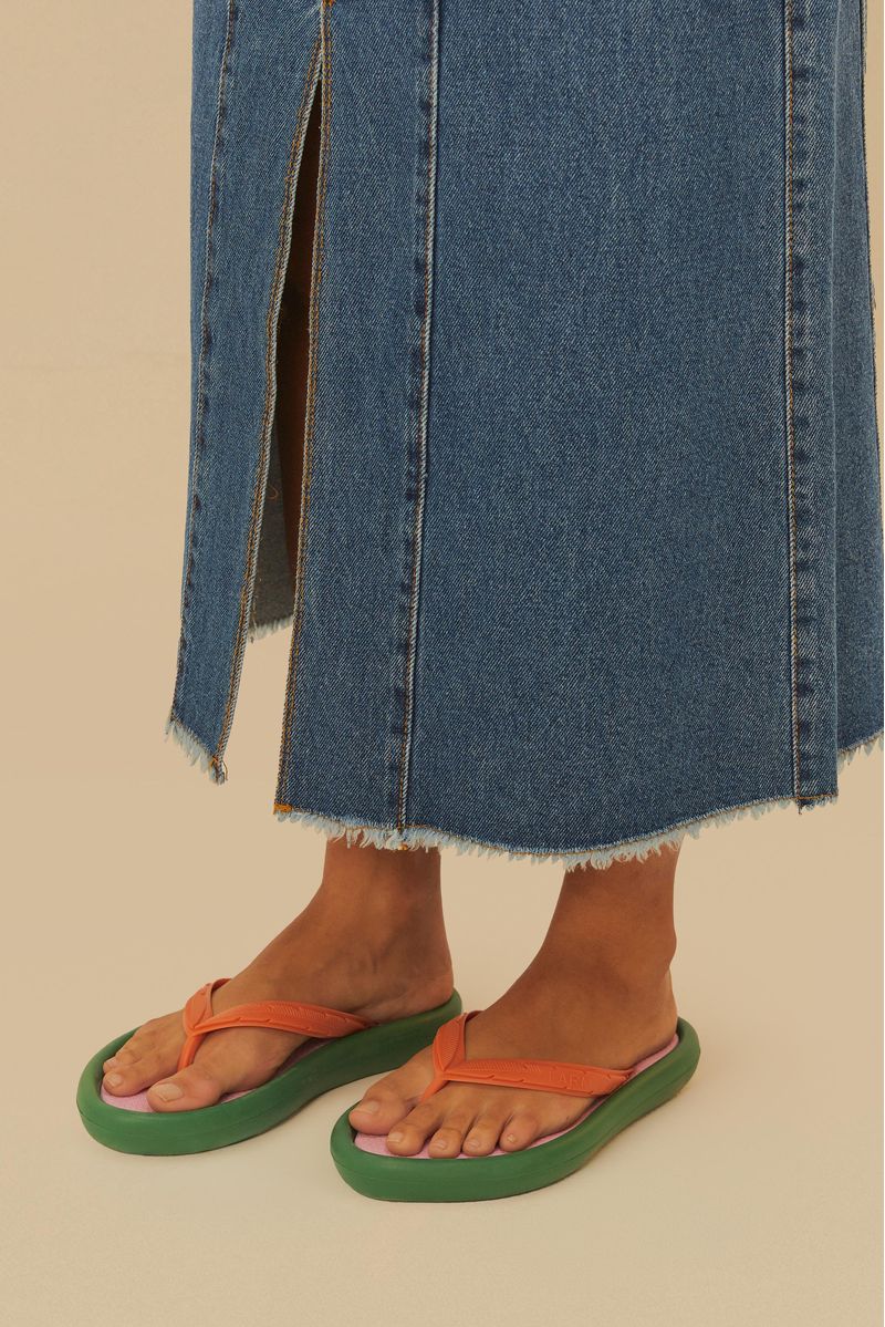 Acercamiento de las chanclas con suela verde y correas naranjas.
