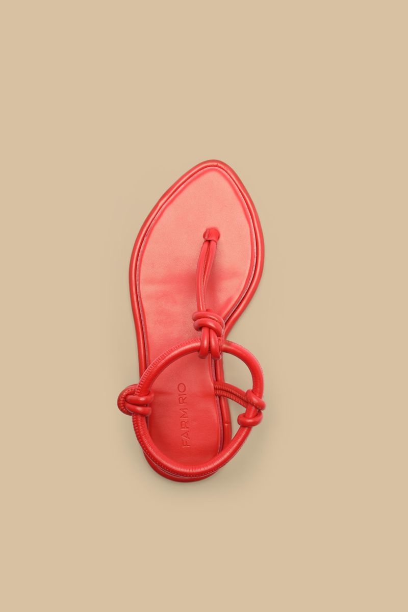Par de sandalias planas de punta foliar rojas con diseño elegante.