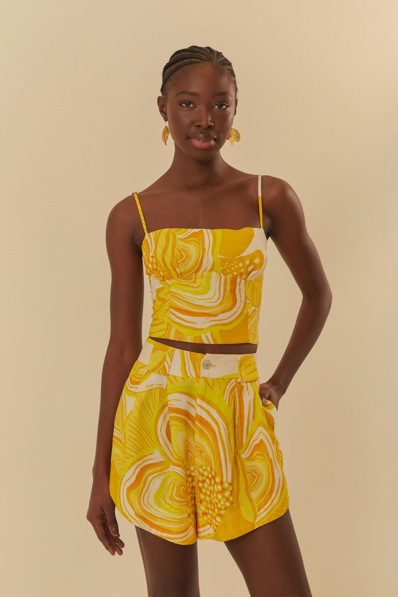 Modelo usando un conjunto de top y short estampado en amarillo y blanco, de frente.