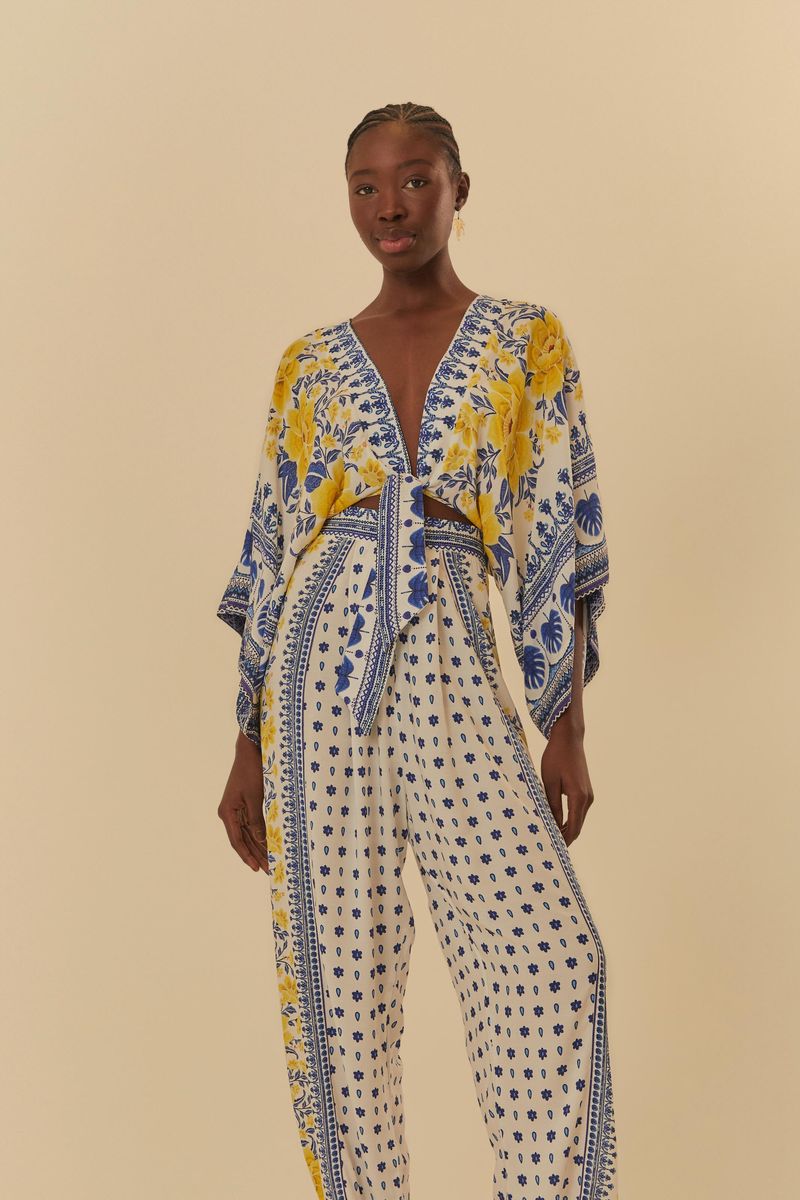 Modelo de frente usando overol con estampado floral azul y amarillo, destacando el escote en V.