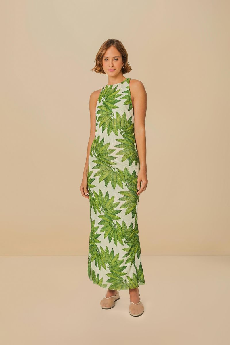 Modelo usando un vestido cropped con estampado de hojas verdes sobre fondo blanco, vista frontal.