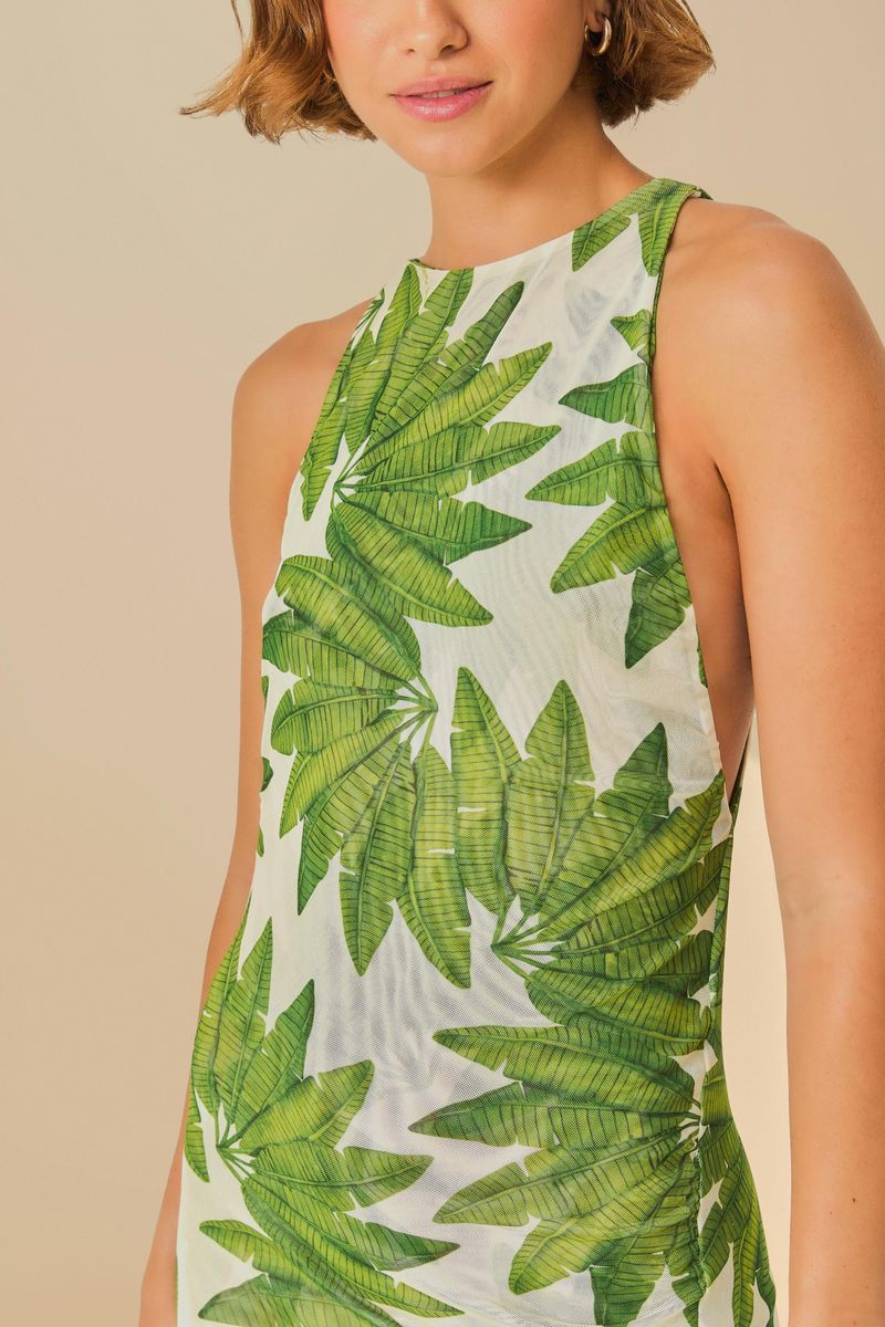 Detalle del escote del vestido cropped con estampado de hojas verdes sobre fondo blanco.