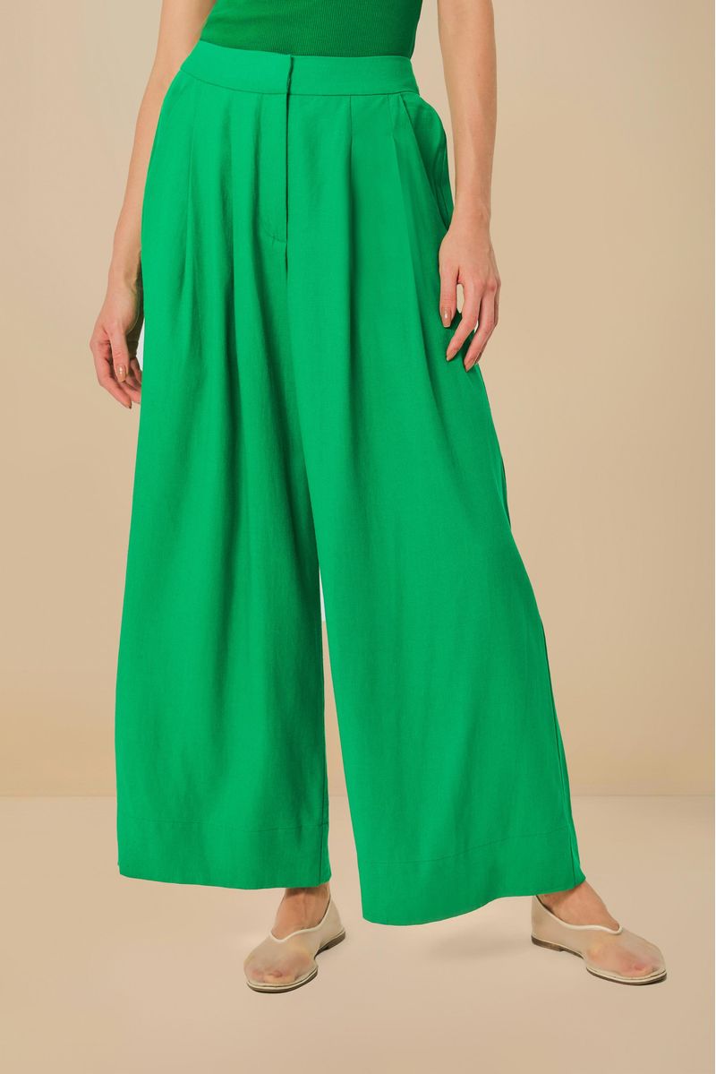 Detalle frontal del pantalón verde mostrando pliegues y bolsillos.
