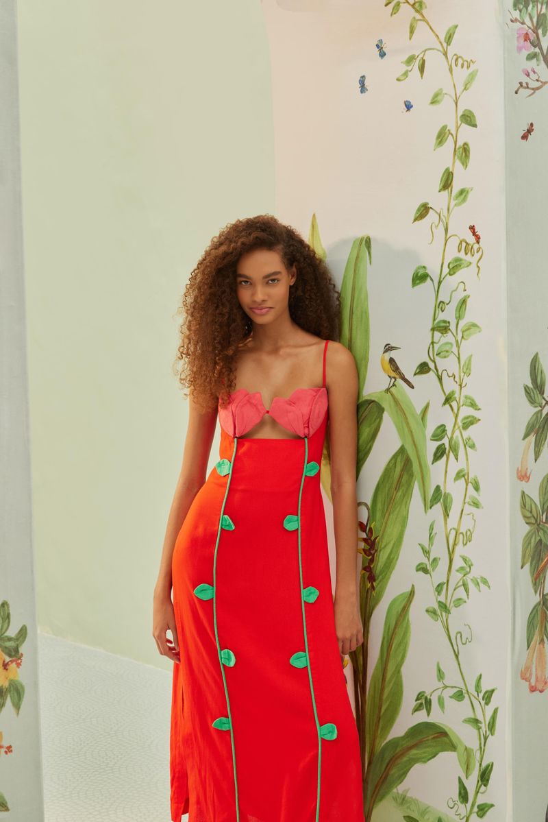 Vestido-rojo-con-detalles-bordados-en-rosa-y-verde-presentado-en-un-entorno-decorado-con-motivos-florales.