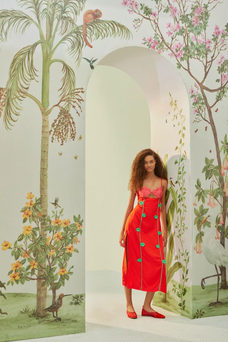 Vestido-rojo-con-bordados-artesanales-en-rosa-y-verde-presentado-en-un-entorno-decorado-con-motivos-florales.