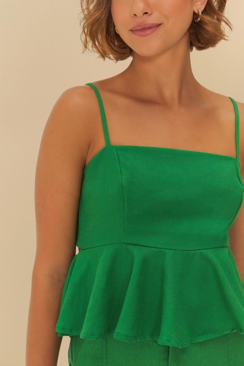 Detalle del escote y tirantes delgados de la blusa verde.