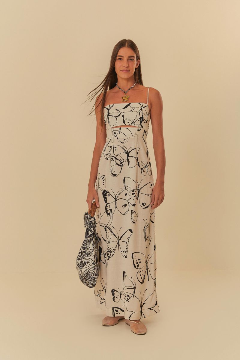 Modelo-usando-vestido-largo-con-estampado-de-mariposas-sosteniendo-un-bolso.