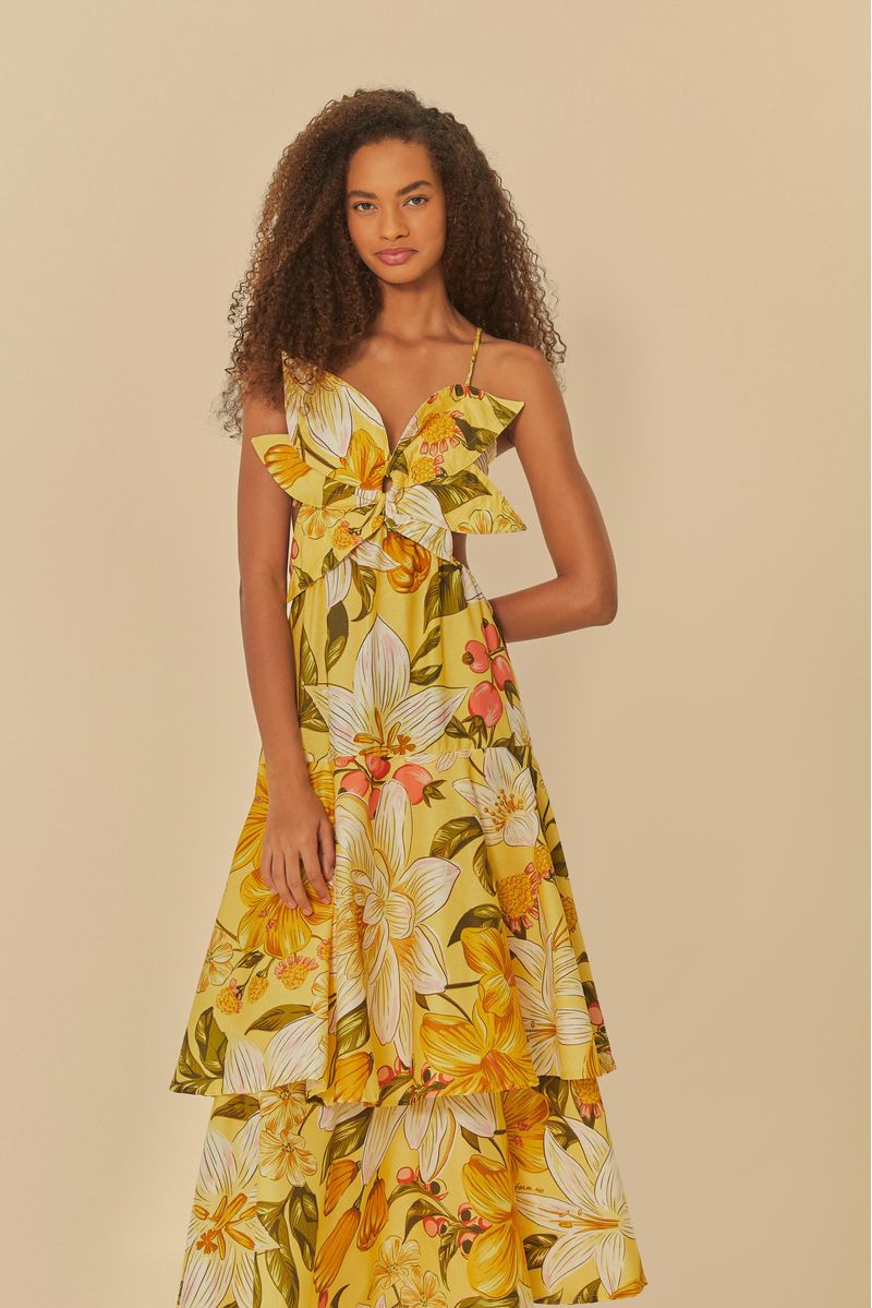 Vestido floral con estampado vibrante de flores amarillas y detalles verdes, exhibido en modelo de frente.