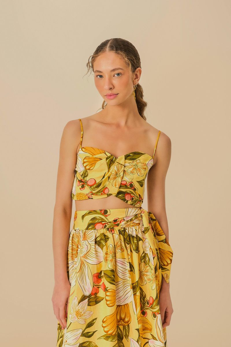 Modelo usando top floral crop con estampado tropical en tonos de amarillo y verde, vista frontal.