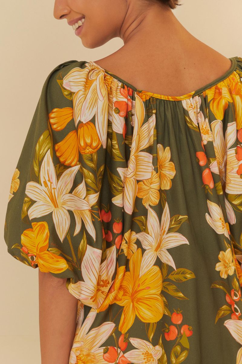 Detalle del estampado floral del vestido, con flores amarillas y blancas sobre fondo verde.