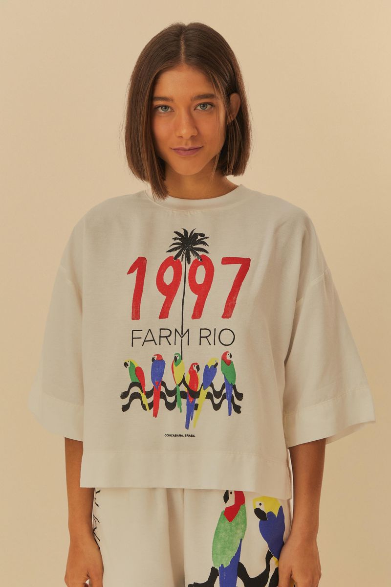 Modelo-usando-una-camiseta-blanca-con-estampado-colorido-de-1997-y-pajaros.