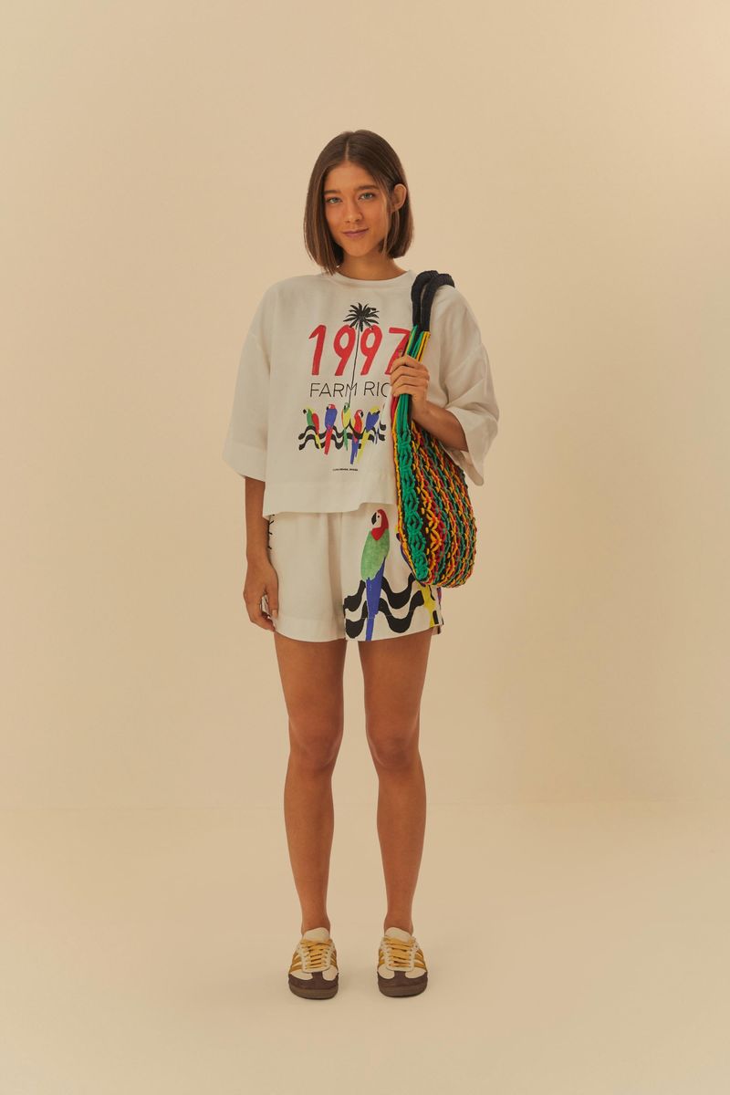 Modelo-de-pie-usando-camiseta-y-shorts-a-juego-sosteniendo-una-bolsa-colorida.