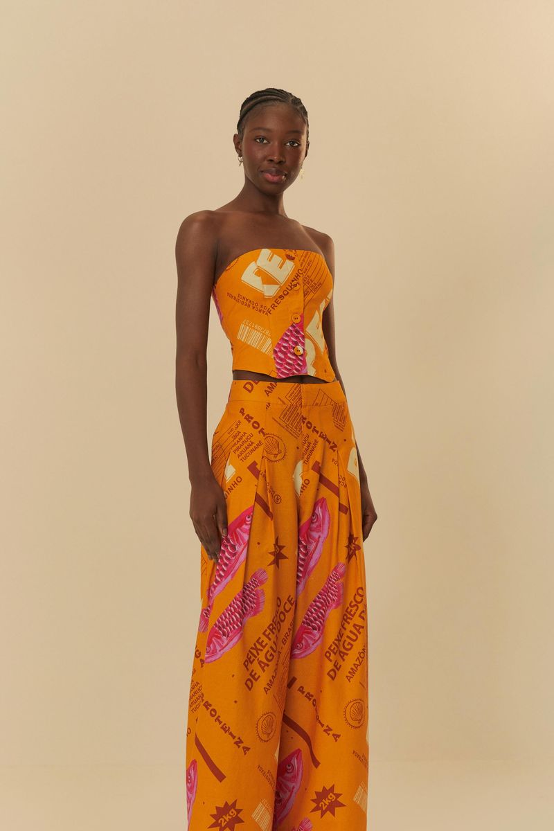 Modelo-vistiendo-pantalon-palazzo-estampado-naranja-con-detalles-en-rosa-y-morado-posando-de-lado