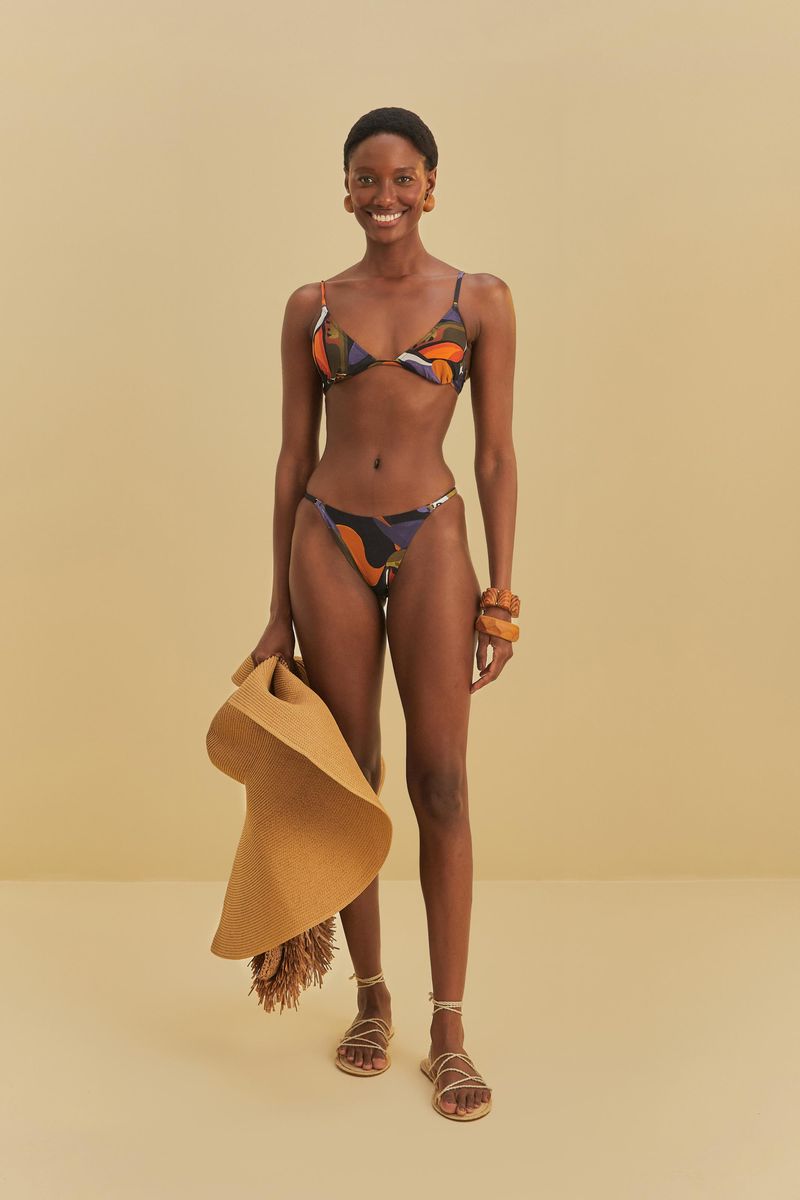 Modelo-usando-un-bikini-media-taza-con-estampado-abstracto-sosteniendo-un-sombrero-de-paja.