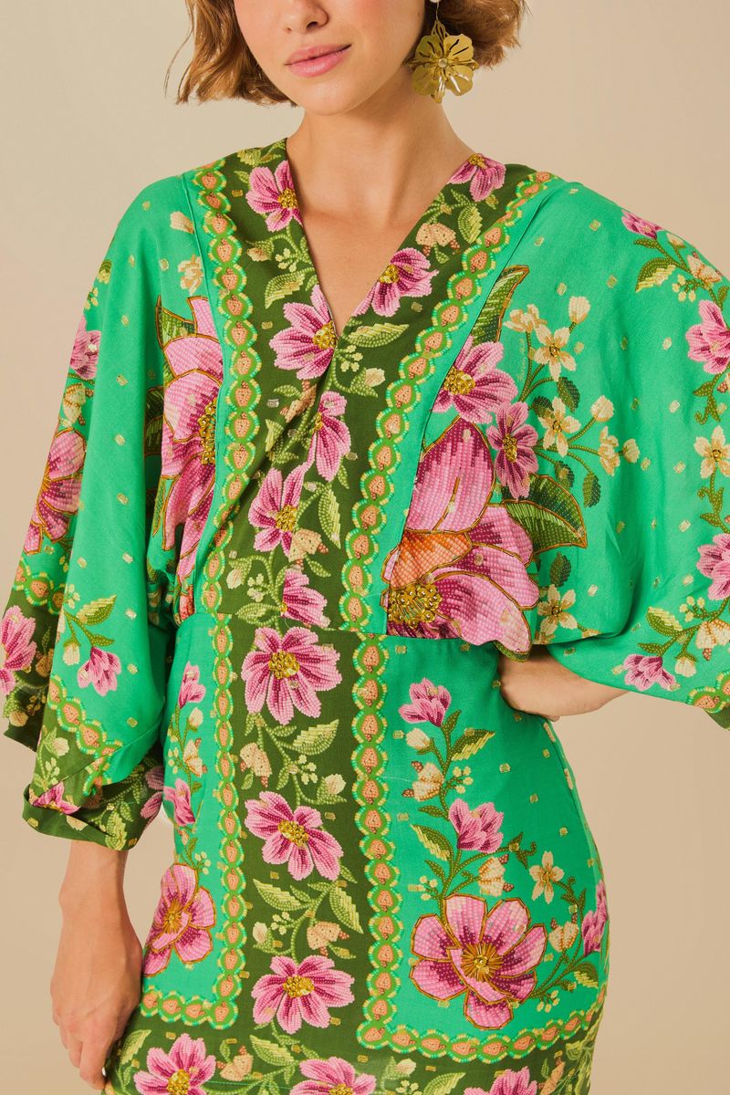 Detalle del escote en V y estampado floral del vestido corto con mangas kimono.