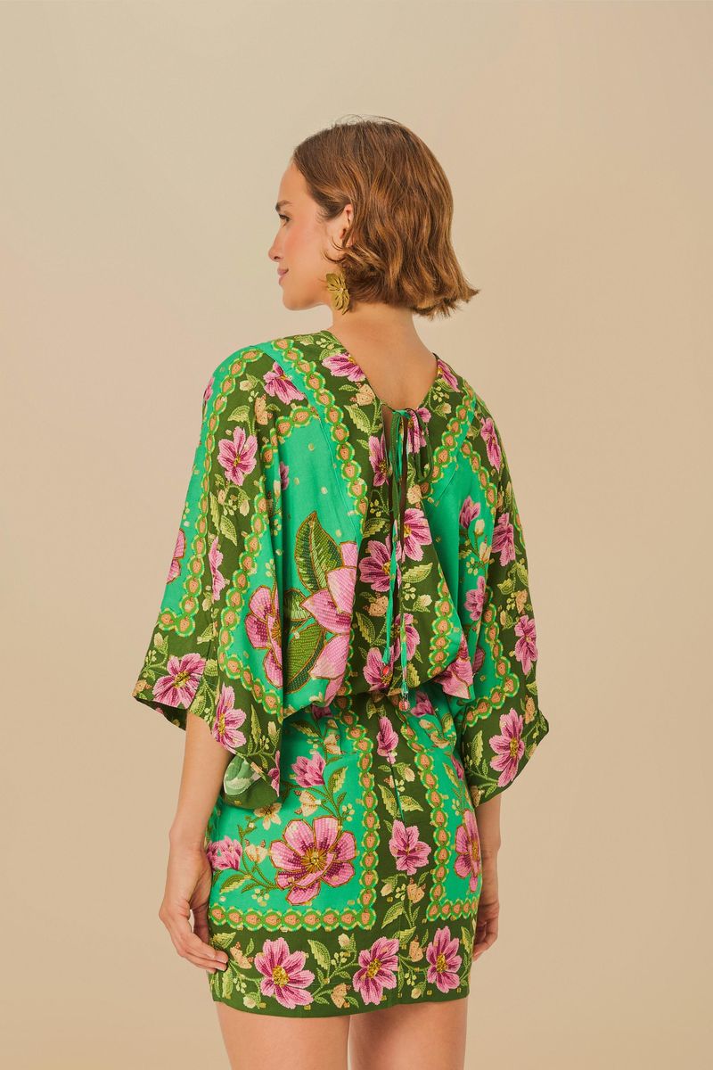 Vista trasera del vestido corto con estampado floral, mostrando el detalle de amarre en la espalda.