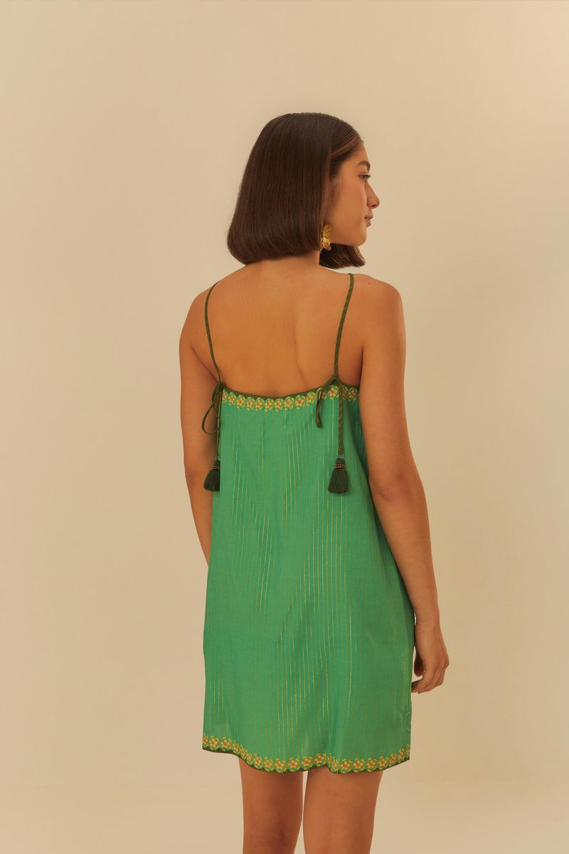Vista trasera del vestido corto verde con estampado de frutas y flores, tirantes finos y detalles decorativos.