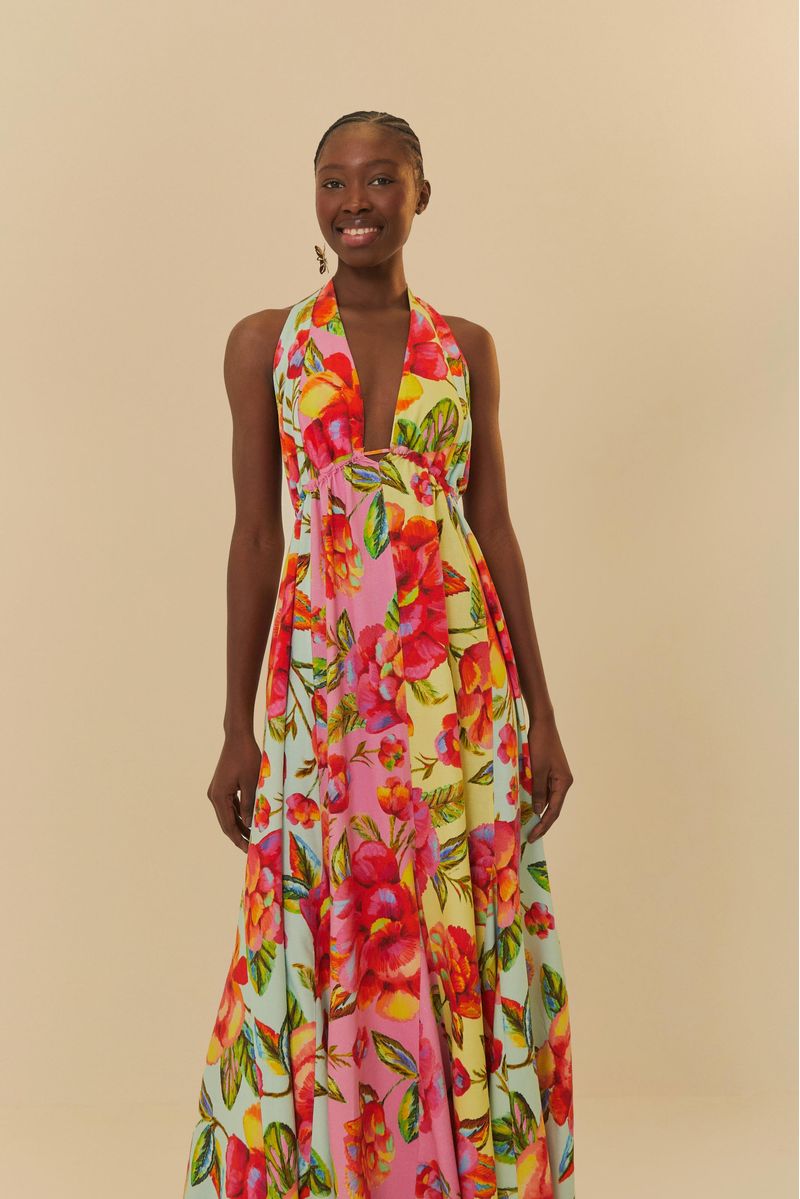 Vestido largo estampado con patrón floral vibrante, escote profundo y tirantes anchos, exhibido sobre un fondo neutro.