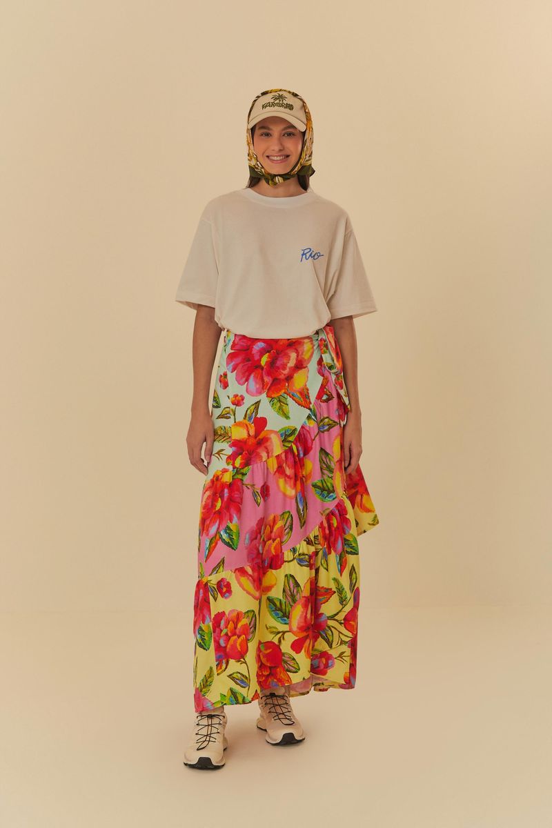 Imagen de una falda larga con estampado floral vibrante en tonos de rosa, amarillo y verde, combinada con una camiseta blanca.