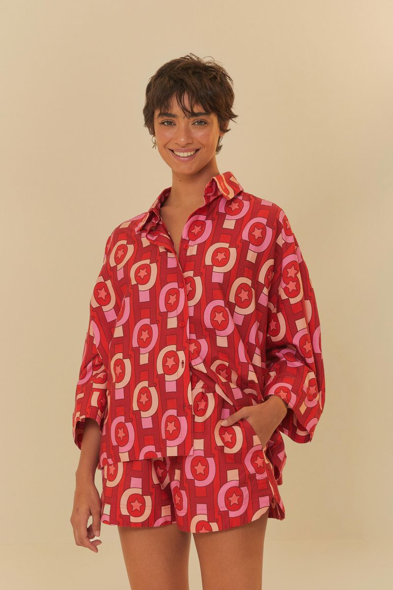 Modelo vistiendo conjunto de camisa y pantalón corto estampado geométrico en tonos de rojo y rosa.