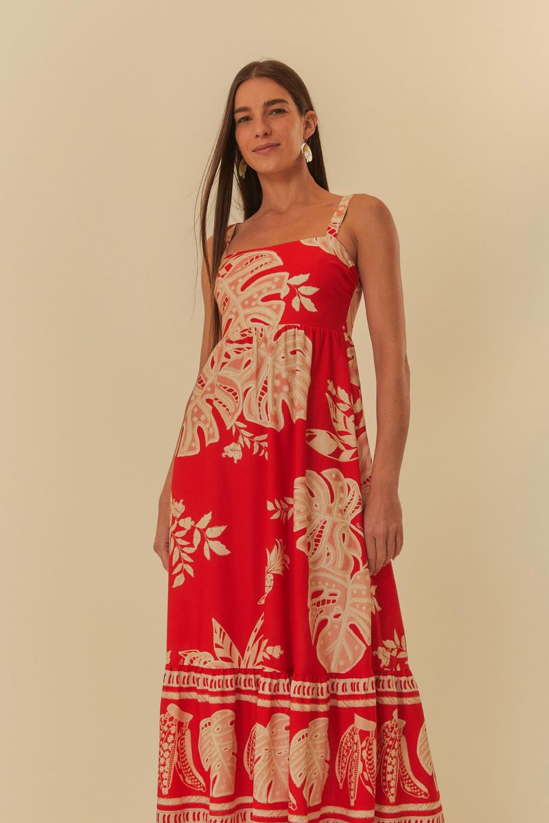 Vestido midi rojo decorado con estampado de hojas y tirantes anchos, mostrado en modelo de perfil.