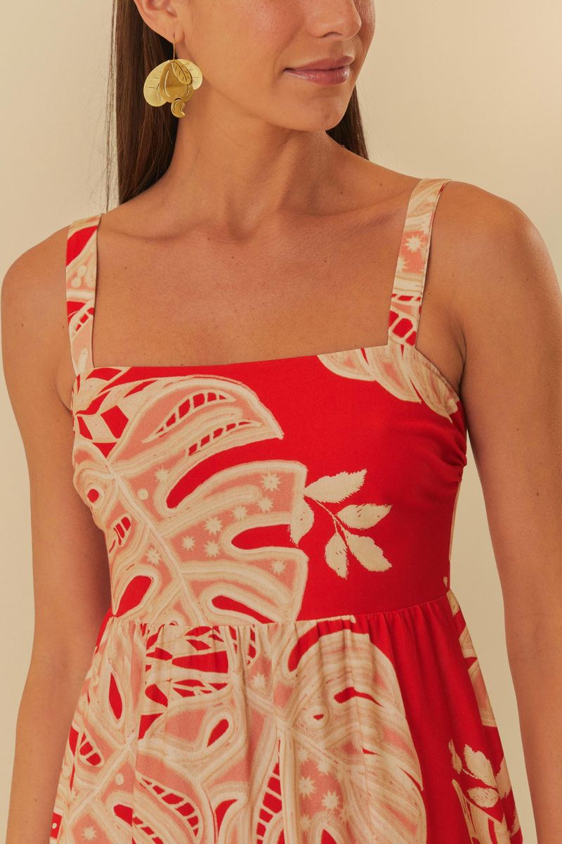 Detalle del escote y tirantes del vestido midi rojo decorado con estampado de hojas.