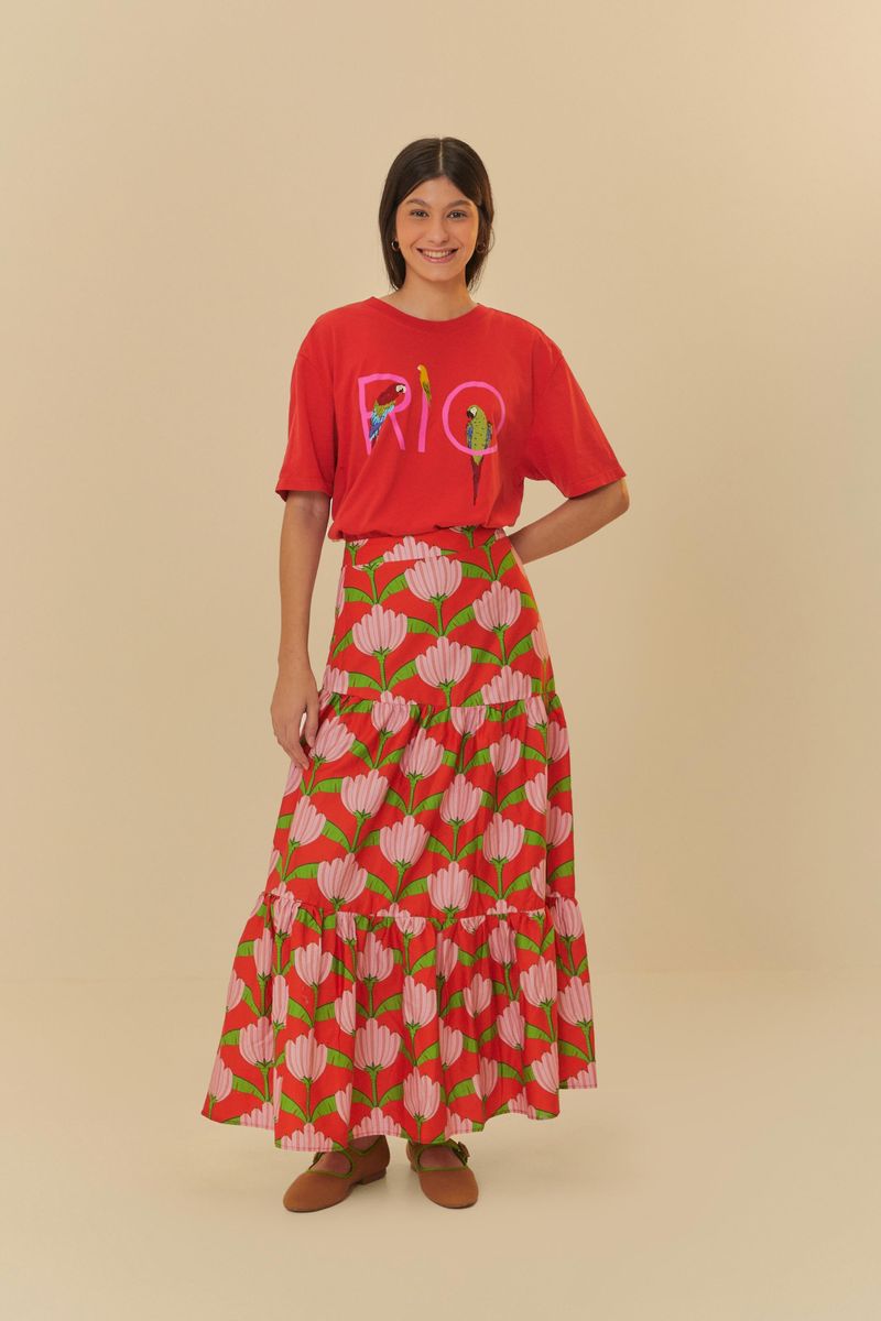 Modelo usando una falda larga estampada con volantes y camiseta roja con la palabra 'RIO' estampada.