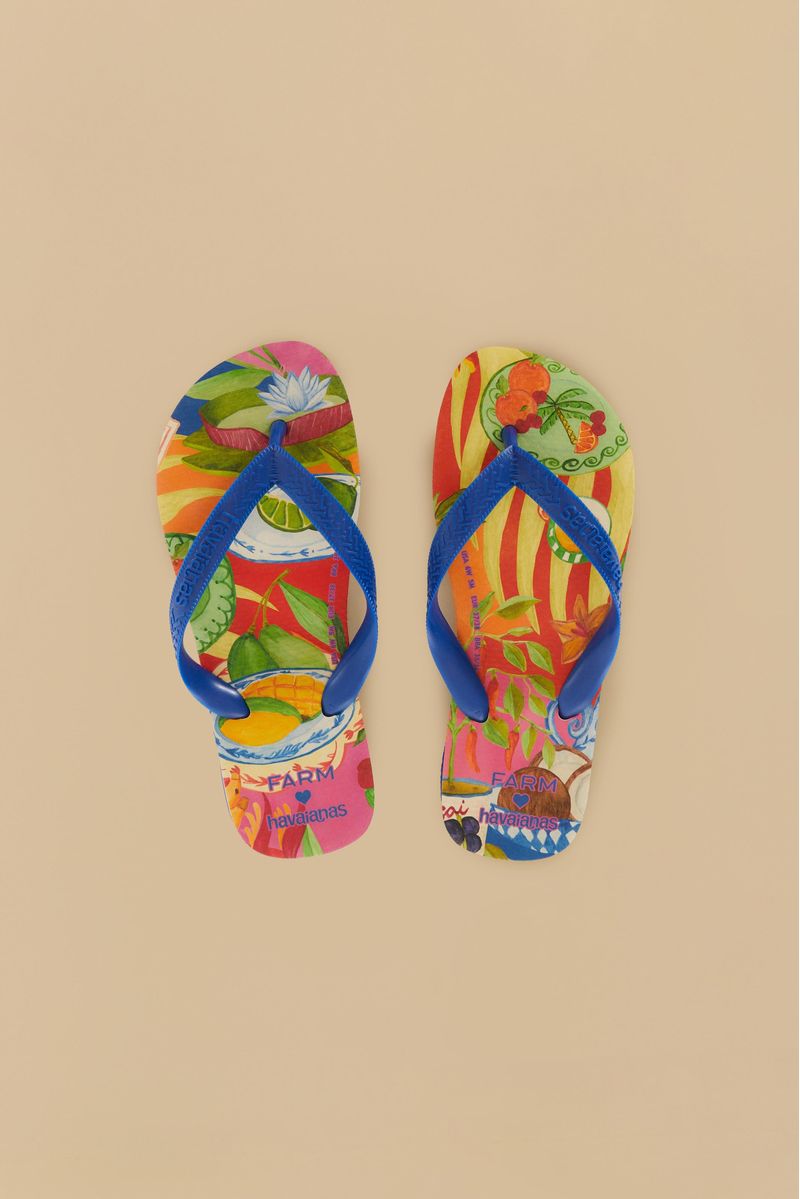 Vista superior de las chanclas Havaianas Picnic que exhiben patrones tropicales coloridos con tiras azules, colocadas una al lado de la otra sobre una superficie beige