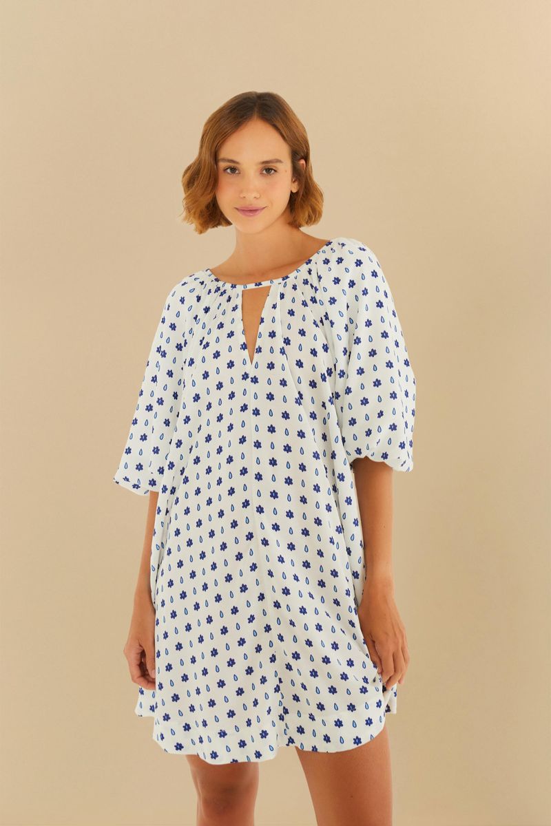 Vestido corto con estampado azul sobre fondo blanco, escote en V y mangas abullonadas.