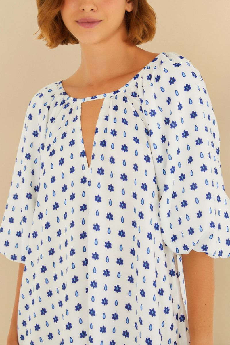 Detalle del escote en V del vestido corto con estampado azul sobre fondo blanco.