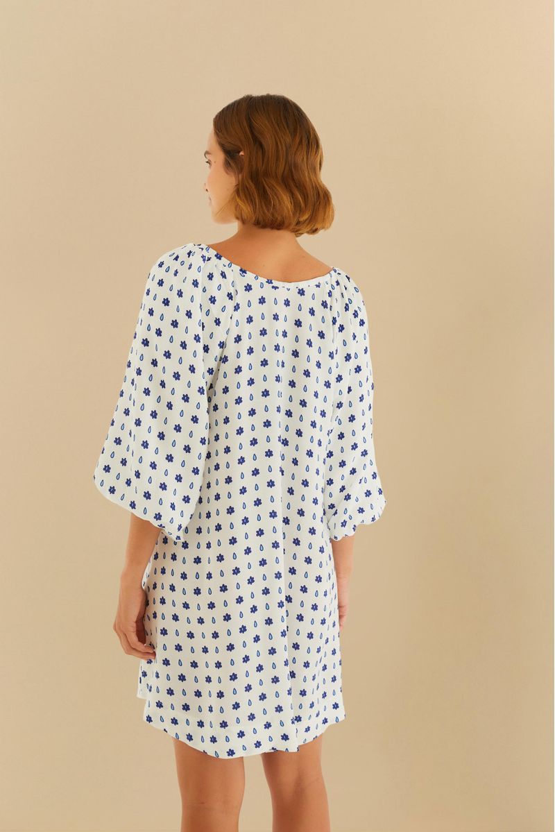 Vista trasera del vestido corto con estampado azul sobre fondo blanco, mostrando caída suelta.