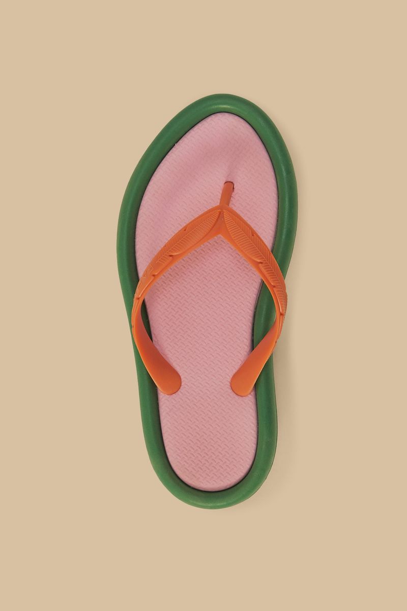 Par de chanclas con suela verde y correas naranjas en un fondo neutro.