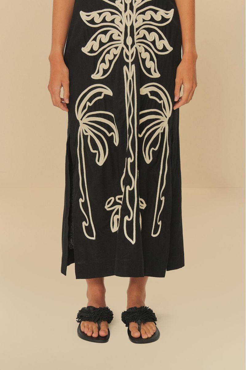 Modelo usando sandalia papete negra con vestido negro decorado.