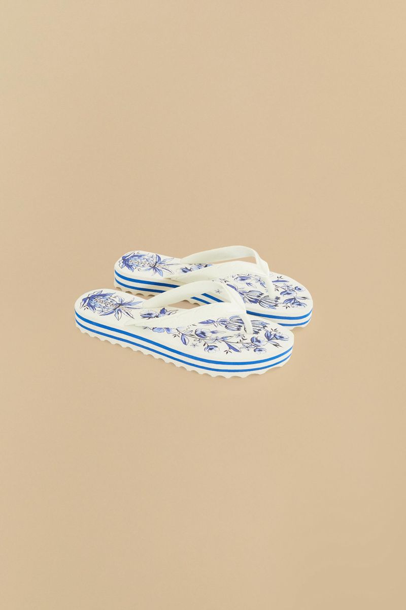 Vista-diagonal-de-dos-chinelos-con-estampado-floral-azul-y-blanco.