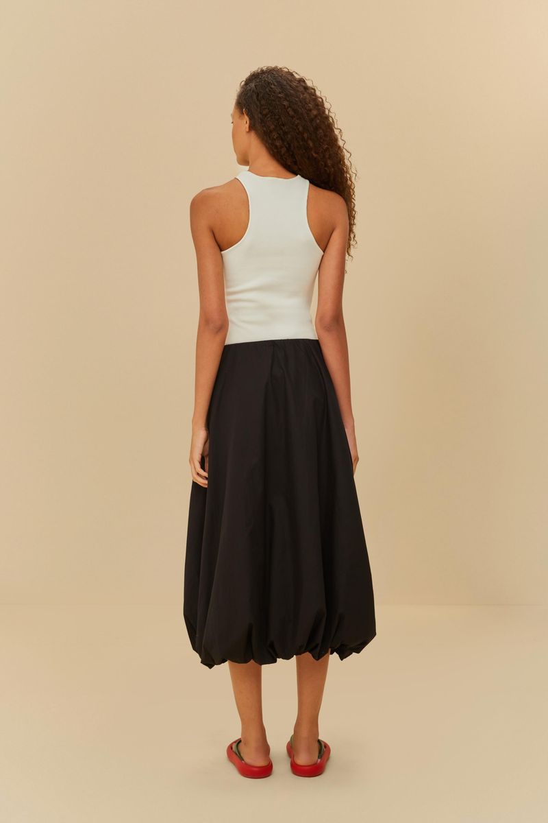 Modelo de espaldas usando falda globo negra con blusa blanca.