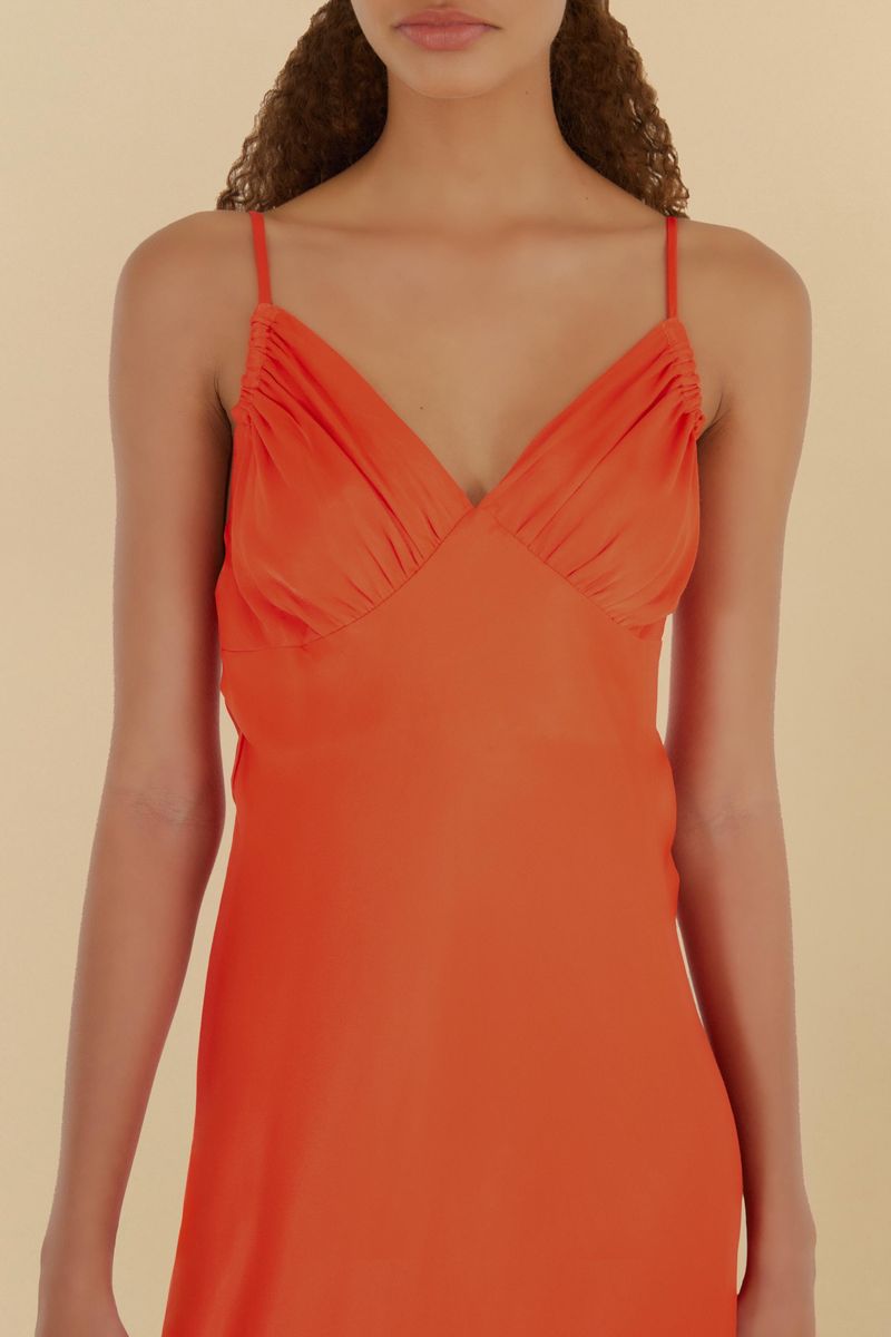 Detalle del escote en V con pliegues del vestido naranja.