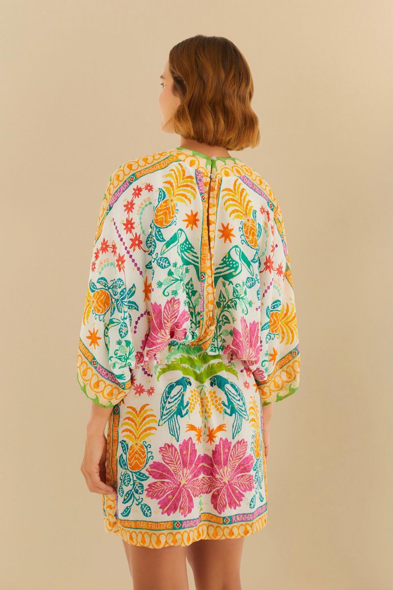 Vista trasera del vestido corto con estampado tropical, destacando el corte suelto.