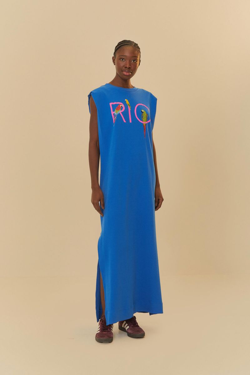 Vista lateral del vestido azul con estampado de guacamayas, mostrando el largo y la abertura lateral.