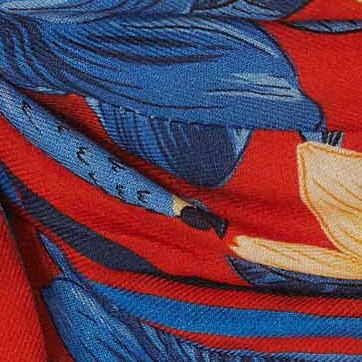 Detalle-del-estampado-floral-del-vestido-destacando-los-elementos-en-azul-y-amarillo-sobre-fondo-rojo.