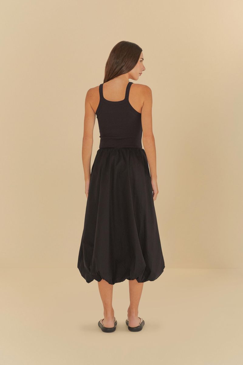 Modelo de espaldas usando falda globo negra con blusa negra.