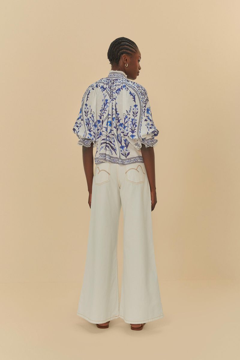 Modelo-usando-pantalones-de-sarga-blancos-con-una-blusa-estampada-azul-y-blanca-vista-trasera.