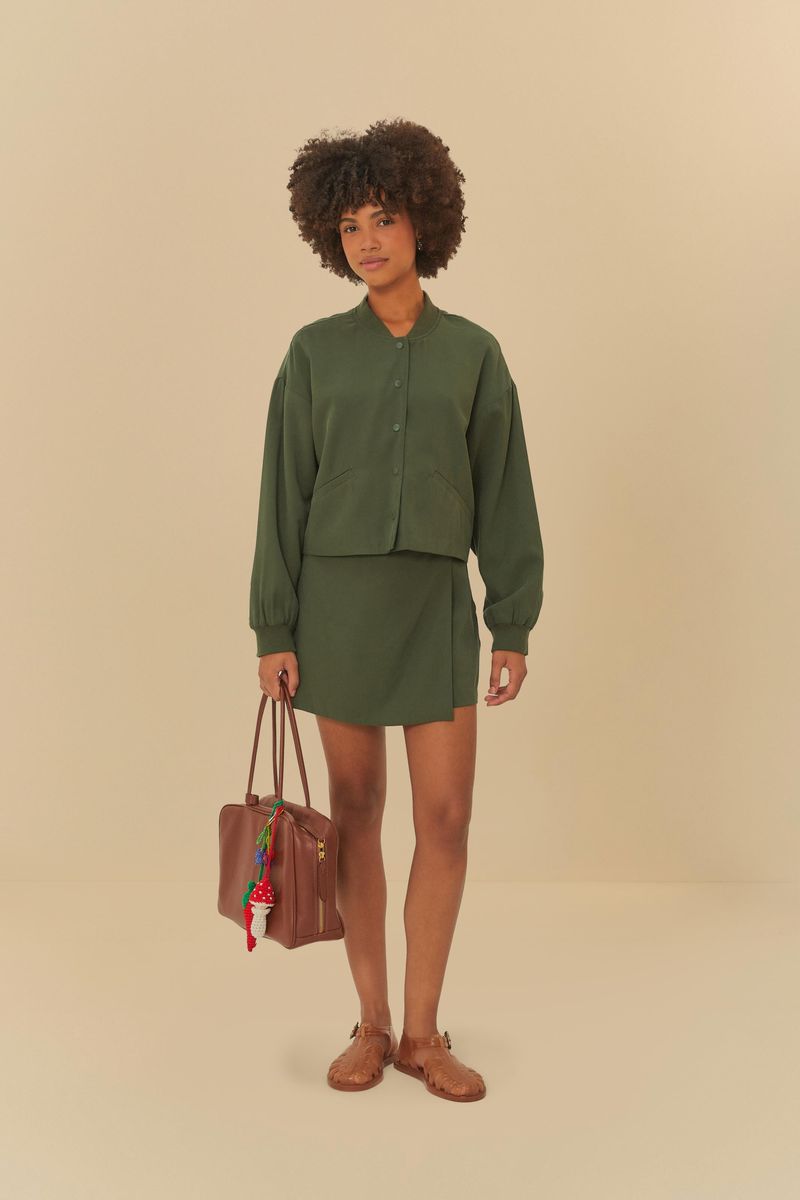 Modelo usando chaqueta bomber verde oscuro con shorts a juego, vista completa.