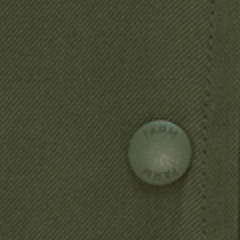Close-up del botón de la chaqueta bomber verde oscuro mostrando detalles del material.
