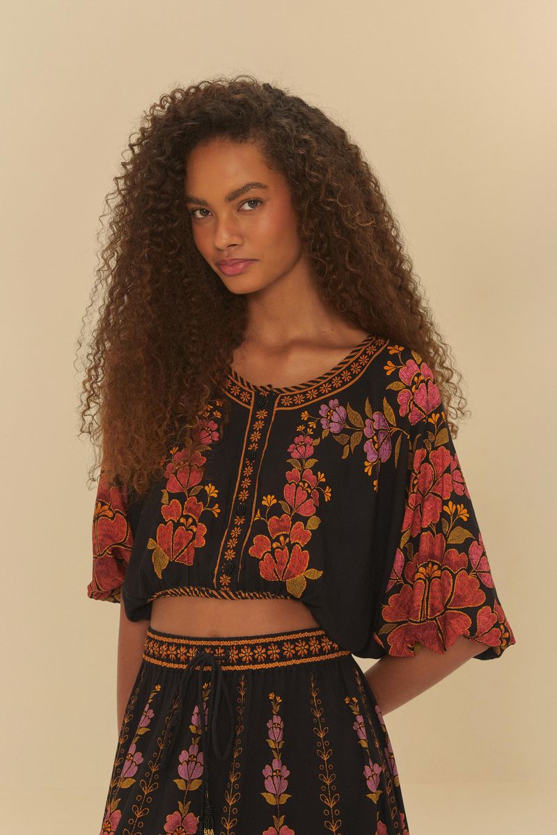 Modelo usando blusa cropped floral con fondo negro, vista frontal.