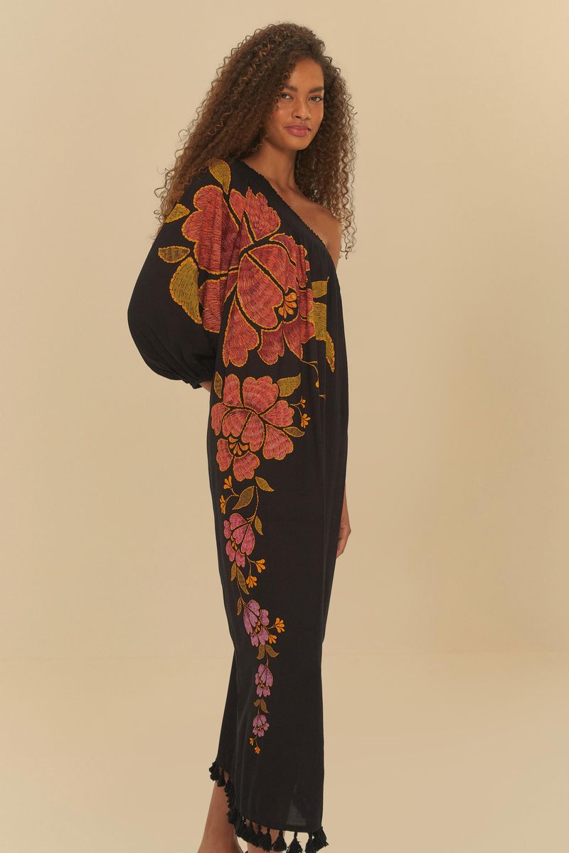 Vista lateral del vestido negro con estampado floral, destacando el diseño asimétrico y la caída fluida.