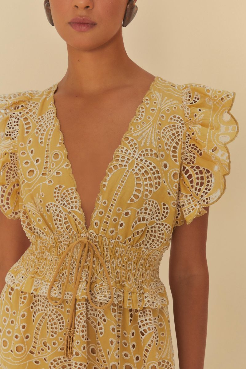 Imagen mostrando el vestido amarillo con detalles en laise y estampado de palmeras, visto de espaldas.